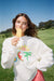 Woman wearing white sweater against a green background