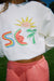 White sweater with colorful graphic ,sun, and palm trees.