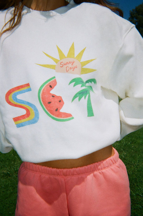 White sweater with colorful graphic ,sun, and palm trees.