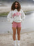 Person wearing a 'Parke' sweatshirt and pink shorts standing on a beach.