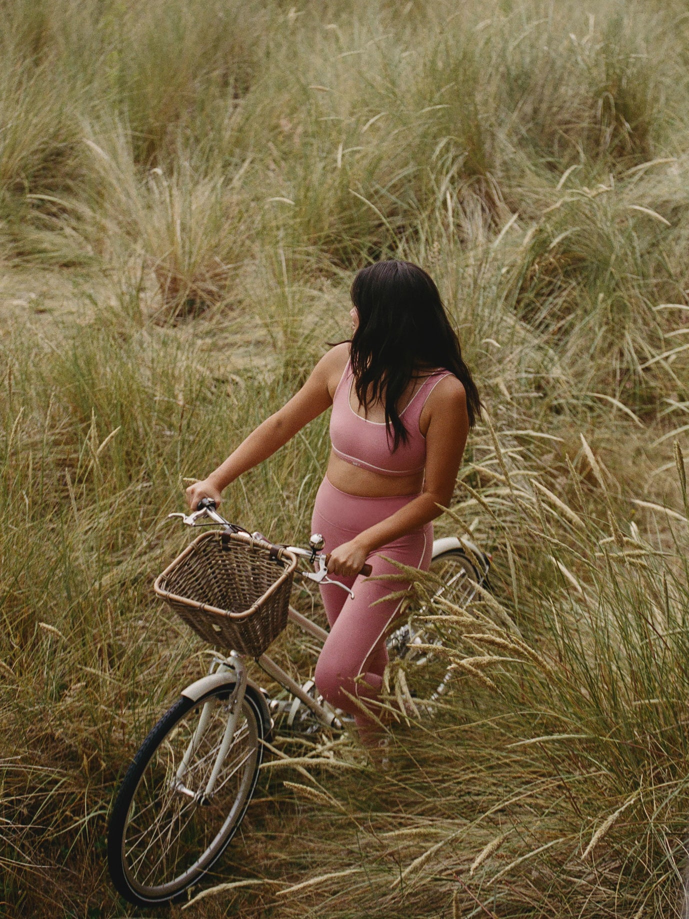 Woman riding a bicycle through tall grass