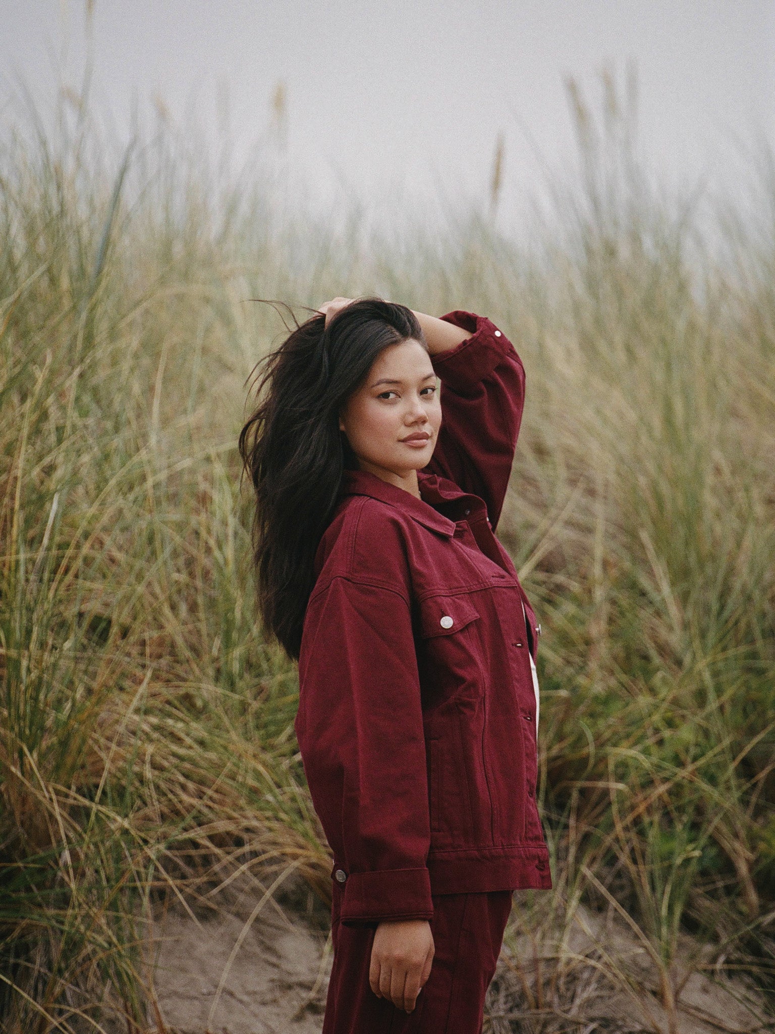 Woman in a red coat standing in tall grass