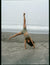 Person doing a handstand on a beach with ocean waves in the background
