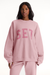Person wearing a pink 'SET' sweatshirt on a white background <model-info>Autumn wears a size S and is 5’7½”, 25” waist, 32” bust.</model-info>