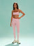 Woman wearing a pink sports bra and leggings set on a light green background