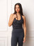 A woman modeling a black and gray striped athletic tank top with a scoop neck, paired with dark gray leggings, standing against a white paneled wall. <model-info>Leah wears a size S and is 5’7”, 25” waist, 32D bust.</model-info>