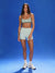 Woman wearing a striped sports bra and light shorts on a blue background