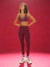 Woman in athletic wear standing against a red background  <model-info>Kushi wears a size S and is 5'8, 24” waist, 32C bust.</model-info>
