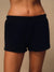 Black sweat shorts worn by a model, shown from the waist down against a neutral beige background. <model-info>Jelene wears a size XS and is 5’7”, 23” waist, 32AB bust.</model-info>