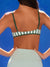 Person wearing a green and white striped sports bra against a blue background