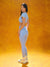 Woman in light blue athletic outfit standing against a yellow background