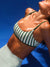 Woman wearing a green and white striped active bra against a blue background <model-info>Logan wears a size XS and is 5’9½”, 24” waist, 32B bust.</model-info>