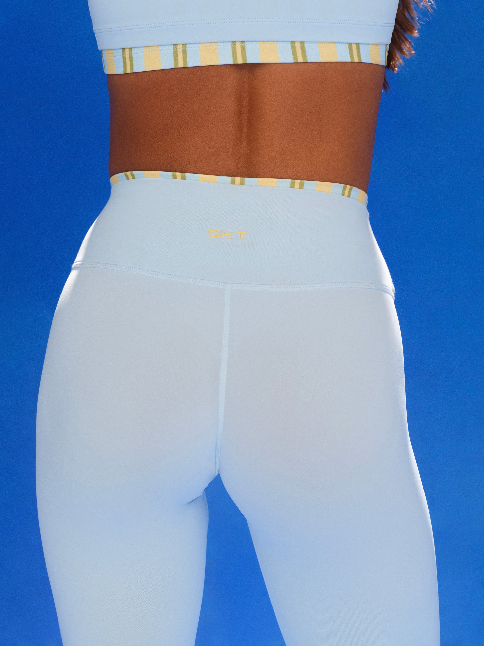 Light blue leggings with a striped waistband and gold accents on a blue background