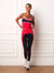 A woman modeling a matching red, black, and white athletic set consisting of a tank top and leggings, standing against a white paneled wall on a wooden floor. <model-info>Courtney wears a size S and is 5’8”, 25” waist, 32B bust.</model-info>