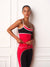 A woman modeling a matching red and black athletic set consisting of a tank top and leggings, standing against a white paneled wall. <model-info>Courtney wears a size XS and is 5’8”, 25” waist, 32B bust.</model-info>
