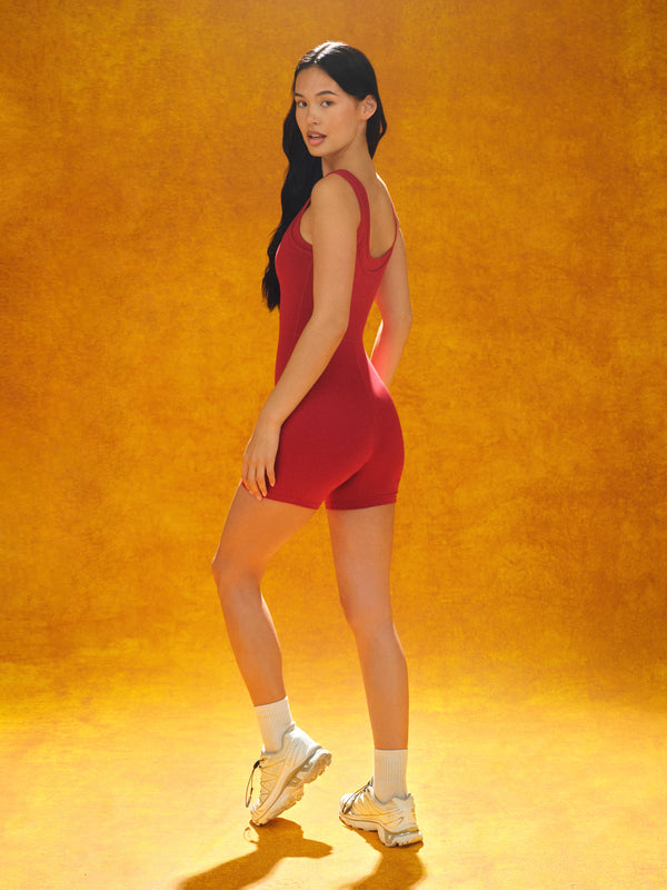 Woman in a red outfit standing against an orange background