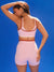 Woman wearing a pink athletic outfit against a blue background