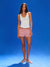 Woman wearing a white tank top and red and white striped shorts on a blue background
