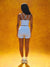 Person wearing a white tank top and shorts set against an orange background