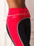 Close-up of a model wearing high-waisted athletic leggings in bright red and black with silver piping and a red drawstring waist.