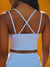 Person wearing a blue sports bra with criss-cross straps against a yellow background