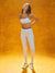 Woman in white sports bra and leggings standing against a yellow background