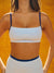 Person wearing a white sports bra with blue straps against an orange background