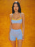 Woman wearing a blue sports bra and shorts set against an orange background