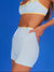 Woman wearing a light blue sports bra and shorts set against a blue background
