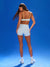 Woman wearing a sports bra and shorts on a blue background