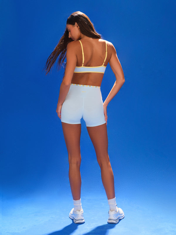 Woman wearing a sports bra and shorts on a blue background