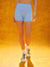 Person wearing light blue athletic shorts on a yellow background