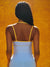 Person wearing a white dress with yellow straps against an orange background