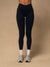 Black high-waisted leggings worn by a model, paired with white socks and gray sneakers, standing against a solid beige studio background.