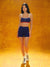 Woman wearing a blue sports bra and shorts set on an orange background