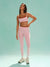 Woman wearing a pink athletic outfit on a light green background <model-info>Kushi wears a size S and is 5'8, 24” waist, 32C bust.</model-info>