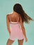 Woman wearing a pink romper against a light green background
