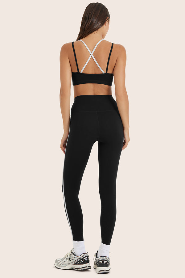 Person wearing a black sports bra and leggings set on a beige background