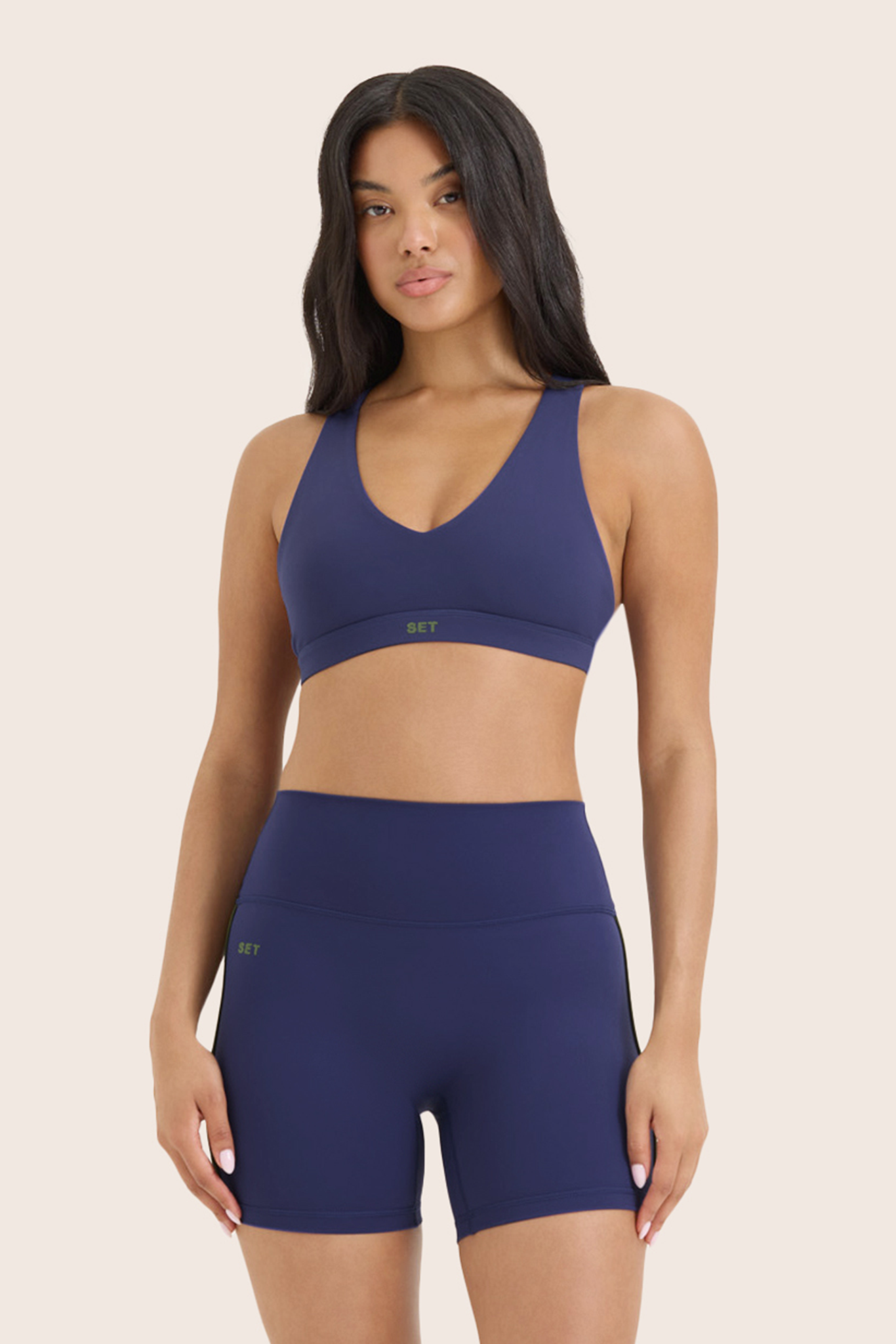 Woman wearing a blue sports bra and shorts set on a beige background 