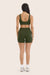 Person wearing a green sports bra and shorts set on a beige background