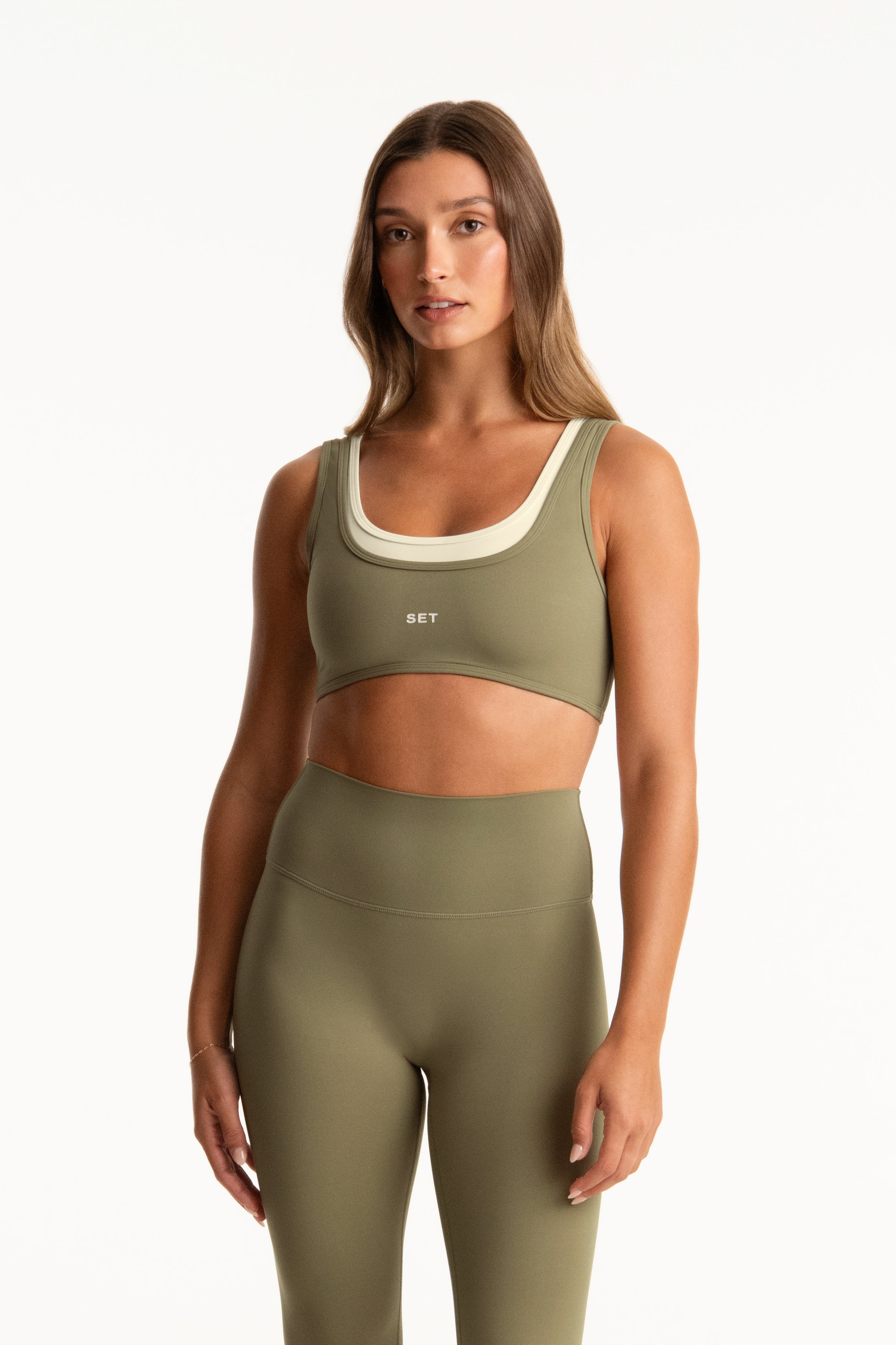 Woman wearing a green sports bra and leggings set on a white background 