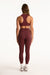 Person wearing a maroon sports bra and leggings set on a white background