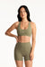 Woman wearing an olive green sports bra and shorts set on a white background <model-info>Jasmine wears a size S and is 5’8”, 25" waist, 36” bust.</model-info>