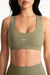 Person wearing a green sports bra with 'SET' branding on a white background