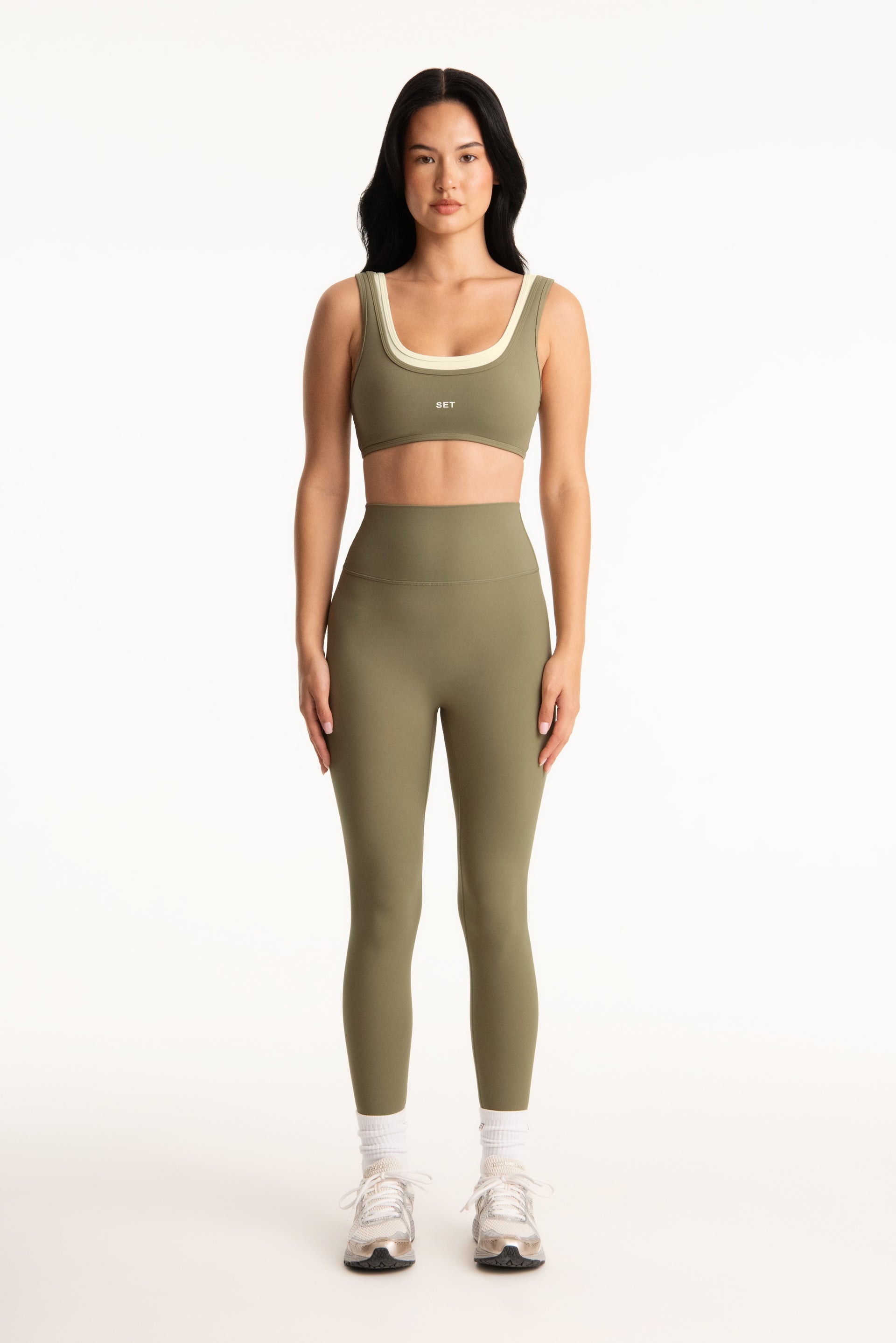 Woman wearing a green sports bra and leggings set on a white background