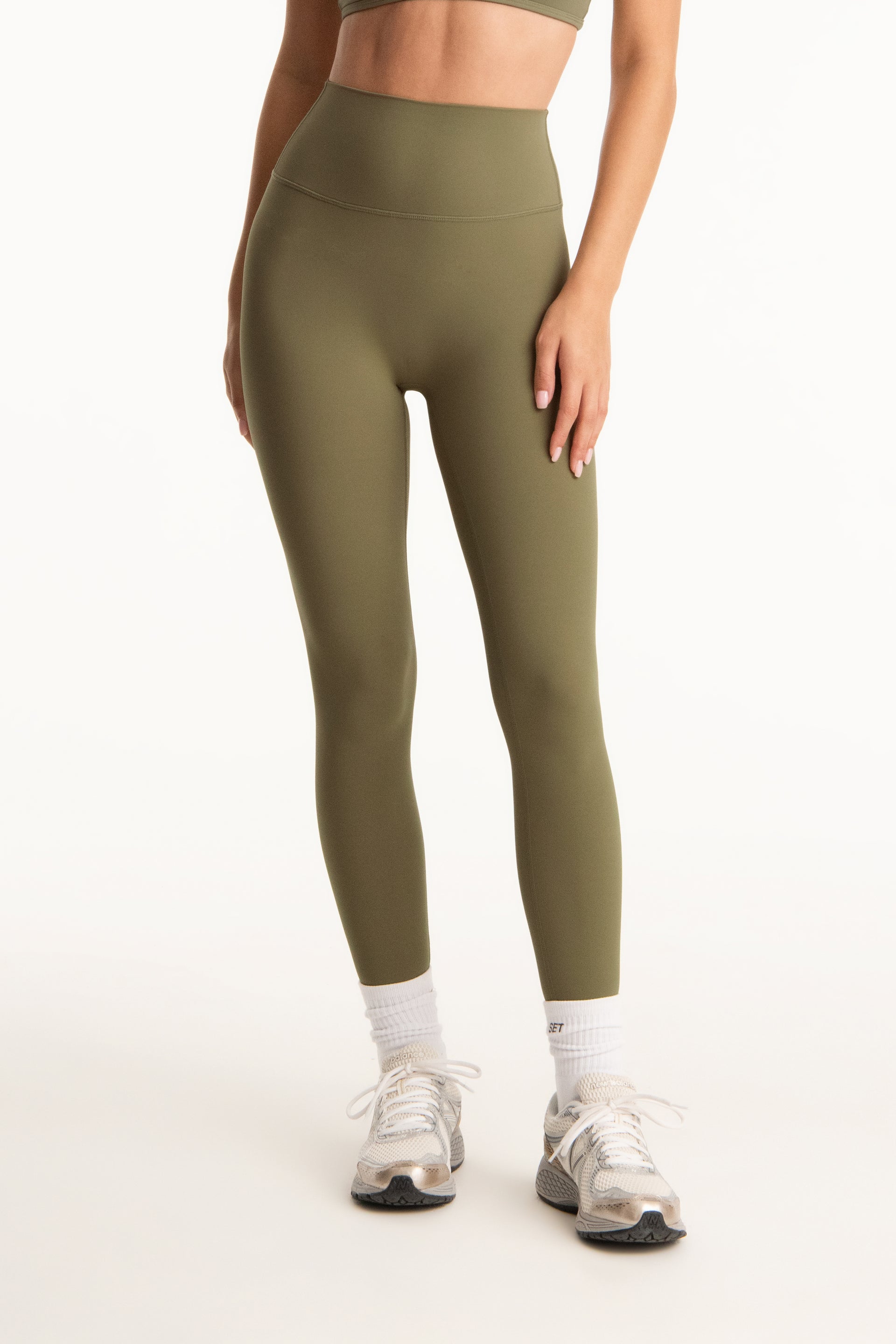 Person wearing olive green leggings on a white background <model-info>Jasmine wears a size S and is 5’8”, 25" waist, 36” bust.</model-info>