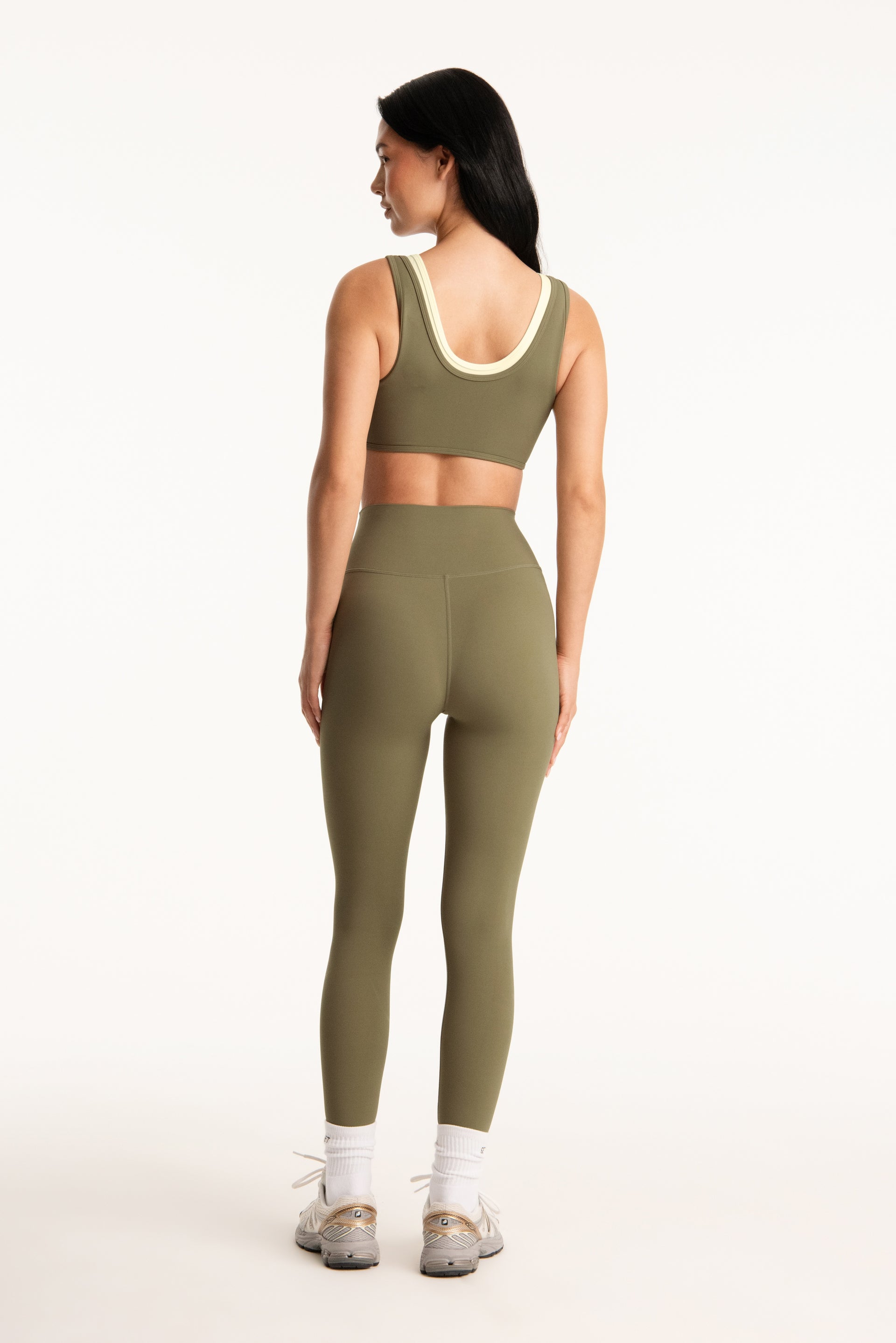 Woman wearing a green sports bra and leggings set on a white background