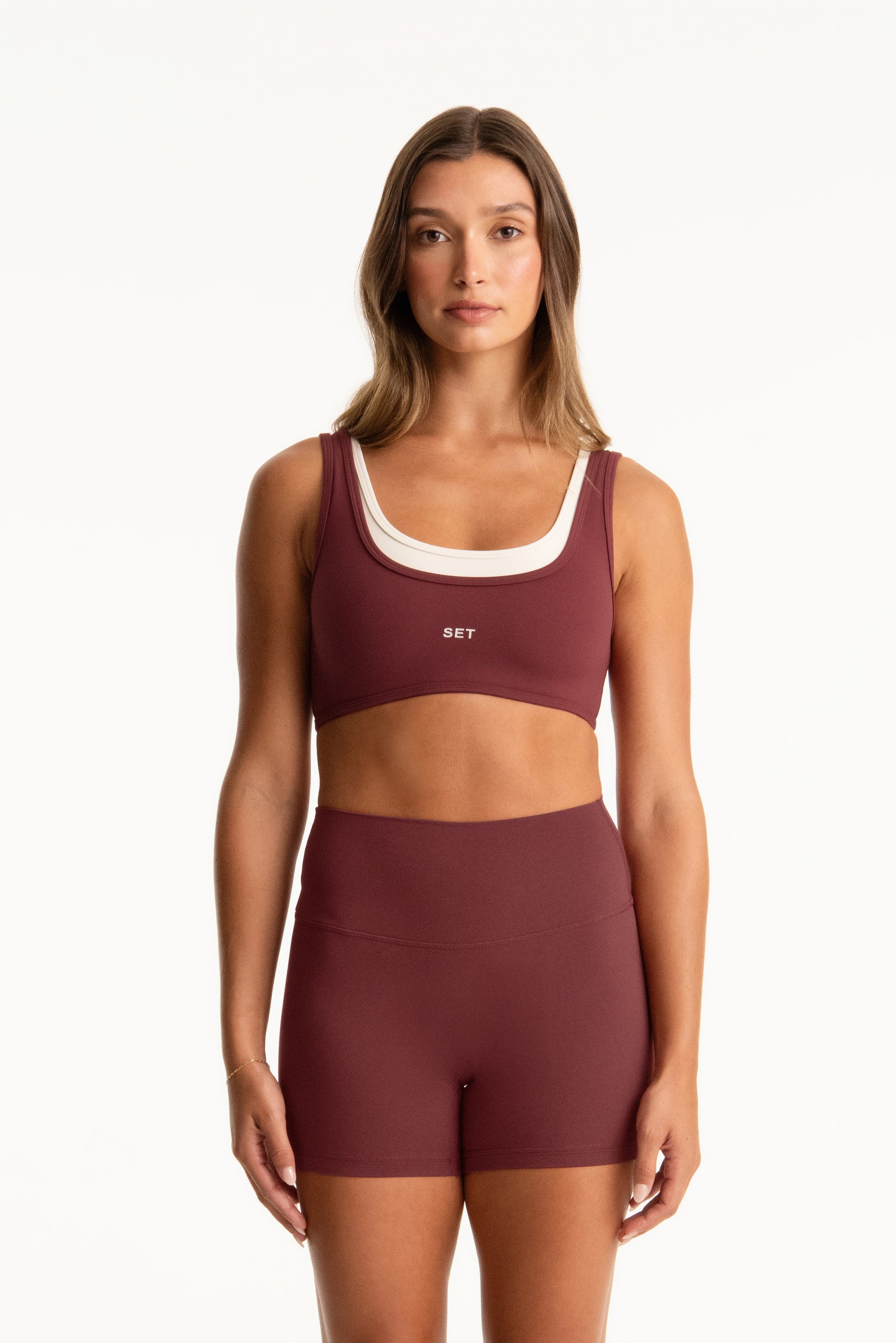 Woman wearing a maroon sports bra and shorts set with 'SET' branding on a white background <model-info>Presley wears a size S and is 5’6”, 26” waist, 33” bust.</model-info>