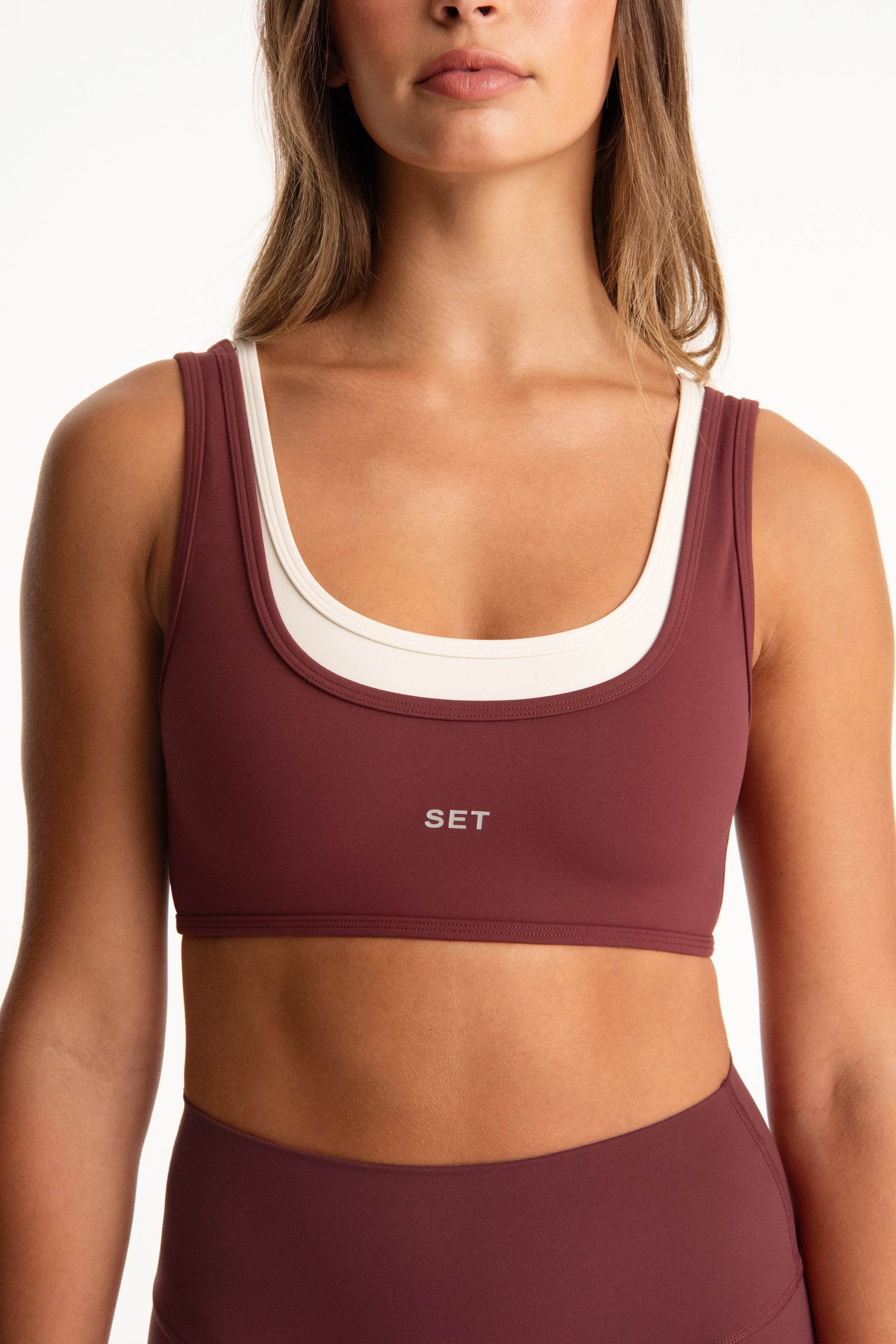 Maroon sports bra with white trim featuring the brand 'SET' on a white background