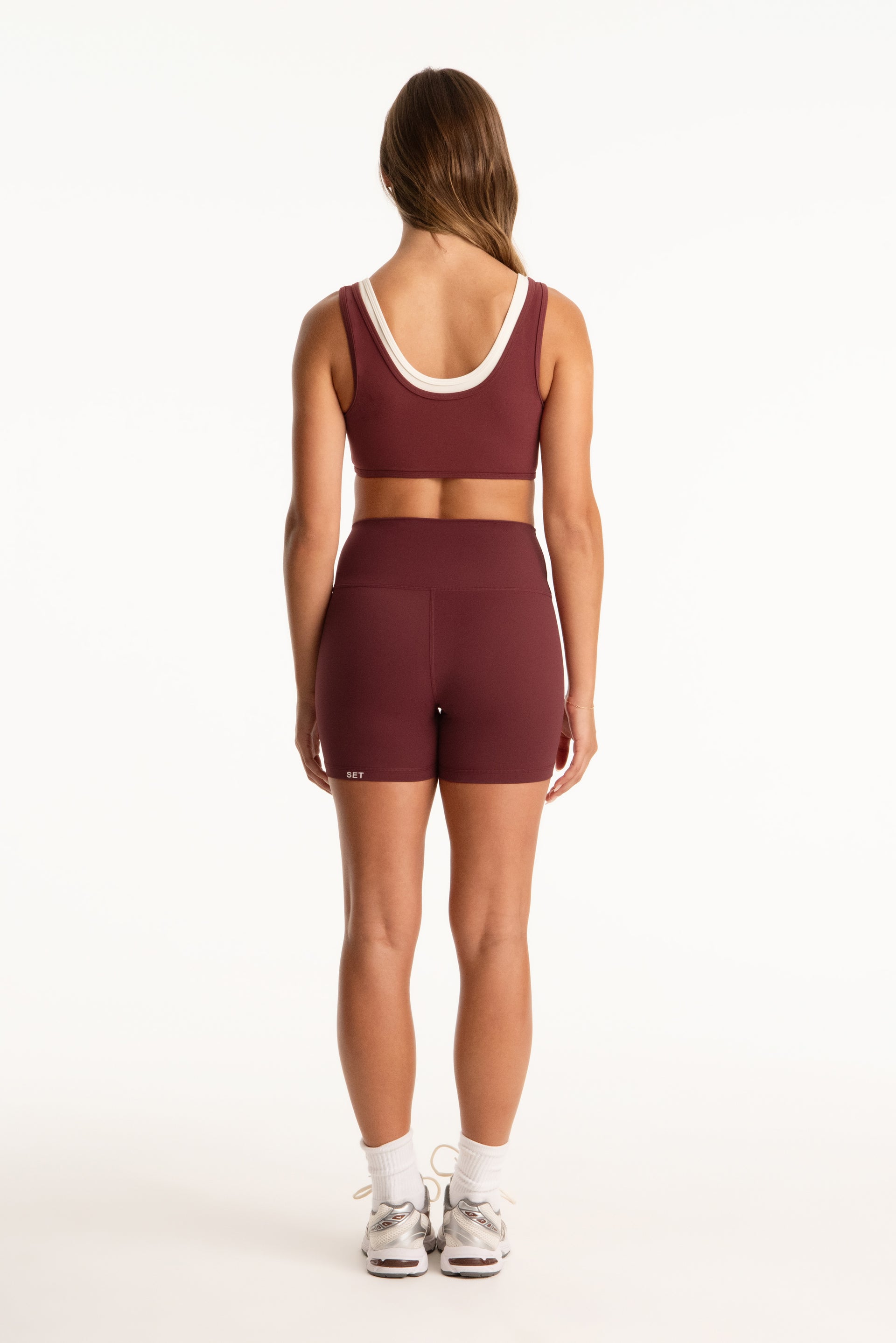 Woman wearing a maroon athletic outfit on a white background